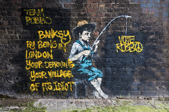 Some idiot has covered Banksy's artwork with puerile graffiti.