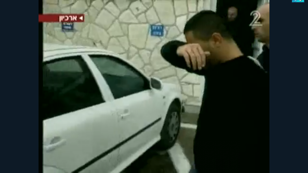 [בתמונה: בן משפחת קראג'ה מובל להארכת מעצר לאחר ניסיון שנכשל להשתלט, ביחד עם משפחת אבוטבול, על אתר למחזור פסולת אשפה במושב בני ציון, ששיך לאדם תמים; אוקטובר 2009. צילום מסך מחדשות 2]