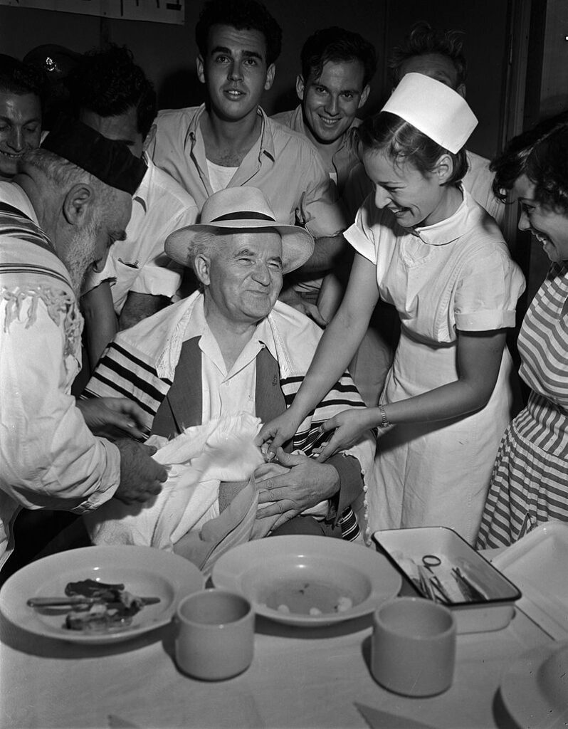 [בתמונה: ראש ממשלת ישראל דוד בן-גוריון משמש כסנדק בברית המילה של הילד הראשון שנולד באילת. התמונה נוצרה והועלתה לויקיפדיה על ידי לשכת העיתונות הממשלתית. שם הצלם אינו מוזכר. קובץ זה הוא בעל רישיון Creative Commons להפצה, תחת רישיון זהה, גרסה: CC BY-SA 3.0]